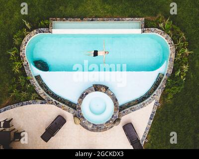 Vista dall'alto uomo solo in una piscina godendo di una soleggiata giornata estiva Foto Stock