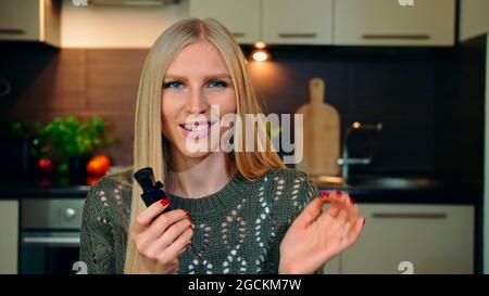 Giovane vlogger profumando profumo. Bella giovane donna che spruzza e profuma profumo piacevole mentre scatta video per la bellezza vlog a casa. Foto Stock
