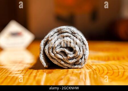 Tovagliolo da tè grigio a tre strati in microfibra arrotolato su una superficie di legno Foto Stock