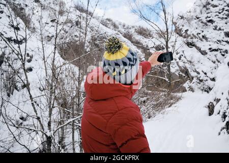 Persona anonima che scatta una foto con il cellulare nel mezzo delle montagne innevate Foto Stock