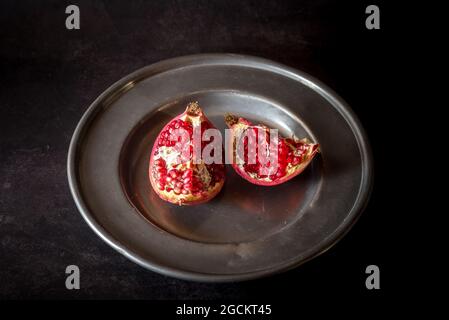 Dall'alto di pezzi di melograno dolce mature serviti su piatto su tavola nera Foto Stock
