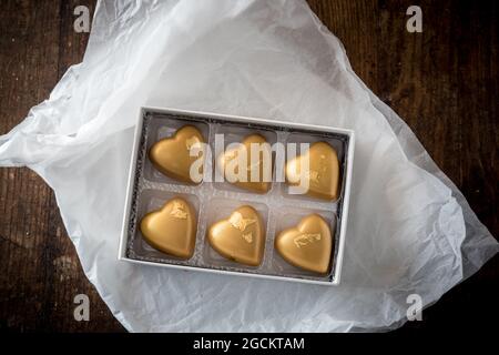 Vista dall'alto di dolci caramelle al cioccolato colorate in scatola posta su un tavolo di legno Foto Stock