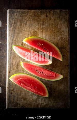 Alto angolo di fette di melone dolce maturo posto su tavolo di legno su sfondo scuro Foto Stock