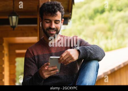 Vista posteriore di un maschio lontano senza volto con lunghi capelli ricci indossare una camicia bianca in piedi sulla soleggiata collina e ammirare vasto valle panoramica con il po tranquillo Foto Stock