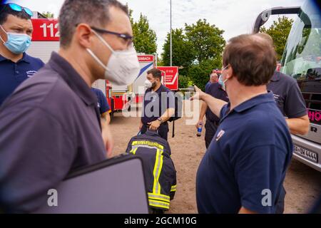 09 agosto 2021, Baviera, Hösbach: Le forze di emergenza si conferiscono al punto di riunione. Per combattere i gravi incendi boschivi in Grecia, l'Assia sta inviando circa 160 forze di protezione civile Assiane, tra cui vigili del fuoco e assistenti dell'Agenzia federale tedesca per il soccorso tecnico (THW), ad Atene e nella regione greca di Attica. La Grecia aveva presentato una richiesta di assistenza nell'ambito del meccanismo di protezione civile dell'UE. Foto: Andreas Arnold/dpa Foto Stock