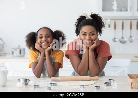 Bella madre afroamericana e figlia che posano durante la cottura Foto Stock