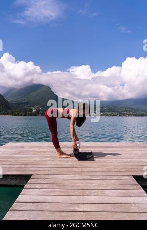 Vista posteriore completa del ciclista FIT femmina in abbigliamento sportivo e casco in bicicletta su strada curva stretta che conduce attraverso verde foresta in estate giorno Foto Stock