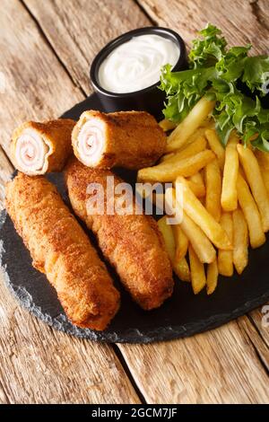 Flamenquines Cordobeses Ricetta involtini di maiale fritti spagnoli con patatine fritte in primo piano nella piastra di ardesia sul tavolo. Verticale Foto Stock
