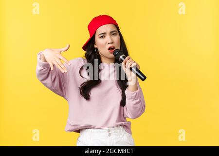 Emozioni della gente, stile di vita e concetto di bellezza. Giovane ragazza elegante e cool rapper in berretto rosso, canto e gesturing, con cui si esibisce Foto Stock