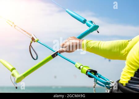 Giovane adulto caucasico fit uomo regolare kite surf board bar in sole uv protezione tuta in giornata di sole luminoso contro il cielo blu in mare o mare riva Foto Stock