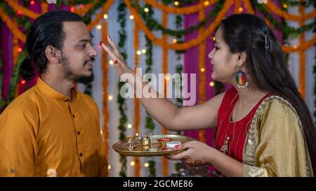 Famiglie indiane che celebrano il festival di Raksha Bandhan un festival per celebrare il legame tra fratello e sorella. Rakhi celebrazione in India. Alimentazione dei dolci, applicazione di tikka. Foto Stock