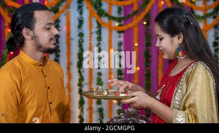 Famiglie indiane che celebrano il festival di Raksha Bandhan un festival per celebrare il legame tra fratello e sorella. Rakhi celebrazione in India. Alimentazione dei dolci, applicazione di tikka. Foto Stock