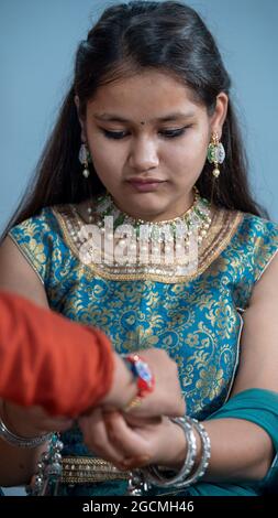 Sorella legando il rakhi, Raksha Bandhan al polso del fratello durante il festival o la cerimonia - Raksha Bandhan celebrato in tutta l'India come amore disinteressato o rapporto tra fratello e sorella Foto Stock