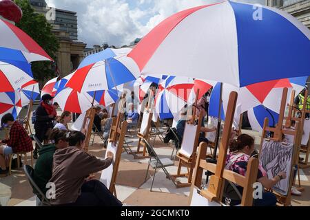 Londra, Regno Unito, 9 agosto 2021: La National Gallery offre lezioni d'arte in Trafalgar Square come parte del Festival Inside out per tutto il mese di agosto. Trenta cavalletti sono stati allestiti -- con ombrelli per il tempo estivo irregolare -- e persone di tutte le età possono cadere in Sketch sulla piazza per la guida nelle abilità di disegno. Anna Watson/Alamy Live News Foto Stock