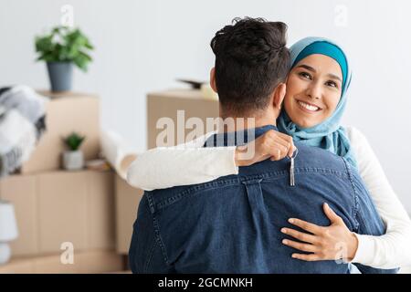 Felice donna musulmana con chiave abbracciando suo marito Foto Stock