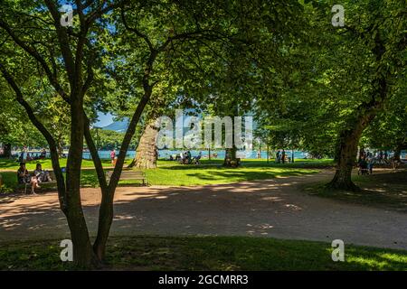 Giardino d'Europa ad Annecy, turisti e gente del posto godono dell'ombra delle piante in questo parco cittadino in una soleggiata giornata estiva. Annecy, Francia Foto Stock