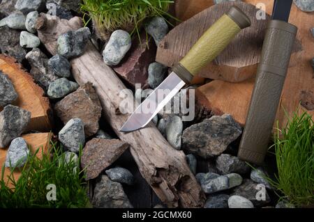 Coltello da caccia con lama fissa sulle pietre. Coltello su pietra e legno. Coltello in acciaio lucido. Foto Stock