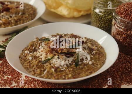 Porridge o gruel a base di riso Navara, fagioli mungs e semi di fieno cosparsi di cocco fresco grattugiato. Conosciuto anche come navara kichadi o uluva kanji Foto Stock