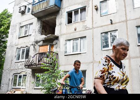 Krasnogorivka, Ucraina. 8 agosto 2021. I residenti di Krasnogorivka passa dall'appartamento che è stato distrutto da Shelling.A condominio residenziale a Krasnogorivka, è stato sgusciato la mattina del 5 agosto. Un civile è stato gravemente ferito nel suo appartamento. Il conflitto armato nell'Ucraina orientale continua a pagare un tributo elevato ai civili, dalla minaccia alla loro sicurezza fisica alla limitazione dell'accesso a cibo, medicinali, alloggi adeguati e scuole. Credit: SOPA Images Limited/Alamy Live News Foto Stock