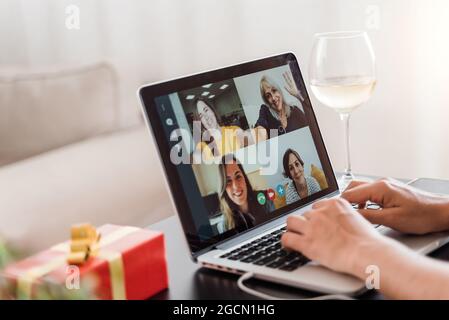 Multi generazionale famiglia in videochiamata per celebrare natale online in conferenza di gruppo meeting con vino utilizzando computer portatile - Focus su schermo Foto Stock