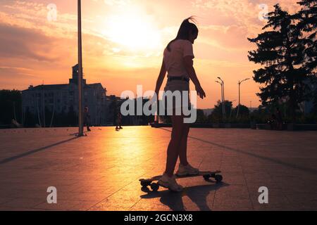 donna skateboarder skateboarder all'alba della città Foto Stock