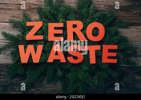 Zero rifiuti di Natale, tagliare le parole sui rami dell'albero di Natale. Concetto pianta piatta su legno rustico. Vista dall'alto Foto Stock