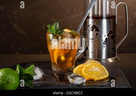 Preparazione del tè freddo. Cucchiaio da bar grande in tazza. Mescolare la bevanda fredda con un cucchiaio. Vista frontale. Foto Stock