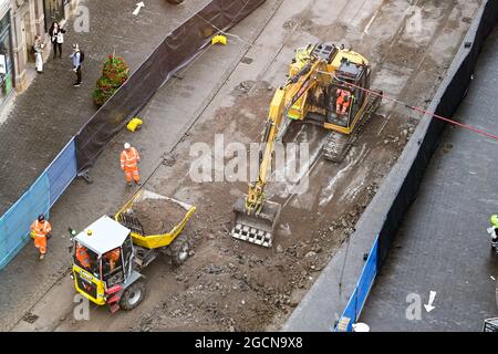 Birmingham, Inghilterra - Agosto 2021: Veduta aerea di un escavatore meccanico che scavava la strada e le piste del tram in una delle strade del centro della città. Foto Stock