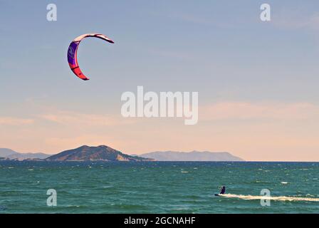 Uomo che pratica il kitesurf nel mare verde smeraldo in Spagna Foto Stock