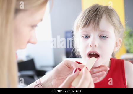 Il medico conduce l'esame fisico della gola della bambina Foto Stock