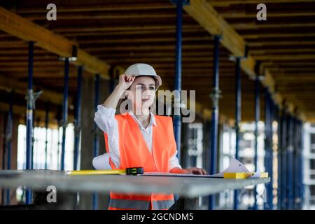 Architetto o ingegnere che lavora, navigando progetto di costruzione interno di cantiere con piano di progetto. Donna, ingegneri di costruzione o architetti che lavorano persone. Foto Stock