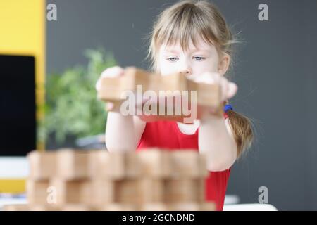 La bambina piega gli ingranaggi di legno sul tavolo Foto Stock