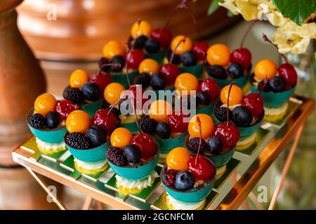Quattro frutti diversi, disposti in ciotole su un tavolo a buffet decorato per una festa. Foto Stock