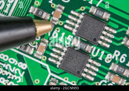 Chip IC a 8 pin su circuito stampato/scheda a circuito stampato legacy. Eventualmente chip driver di linea o chip di memoria flash. Scala dalla punta della penna a sfera accanto al piccolo condensatore. Foto Stock