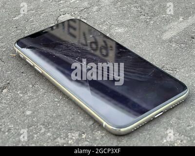 MOSCA, RUSSIA - 29 luglio 2021: Incrinature sul vetro di un telefono cellulare. Si trova sull'asfalto grigio Foto Stock