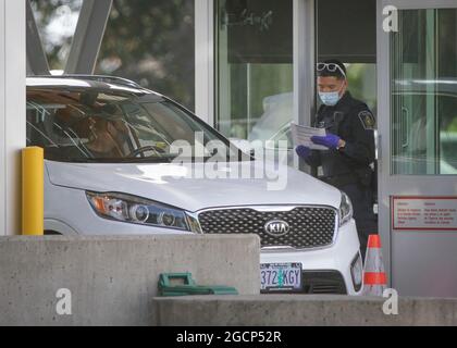 Surrey, Canada. 9 agosto 2021. Un ufficiale di frontiera canadese controlla i documenti di un visitatore degli Stati Uniti all'attraversamento del confine dell'arco della Pace a Surrey, British Columbia, Canada, il 9 agosto 2021. Il Canada ha iniziato unilateralmente a consentire l'ingresso da parte di cittadini statunitensi e residenti permanenti completamente vaccinati lunedì dopo che i due paesi hanno accettato di chiudere il confine a viaggi non essenziali a causa della pandemia COVID-19 17 mesi fa. Credit: Liang Sen/Xinhua/Alamy Live News Foto Stock