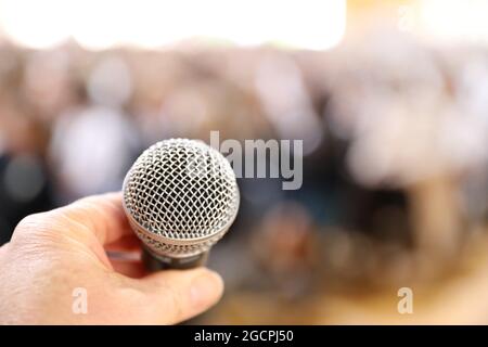 Un microfono molto vicino con una mano circa per chiuderlo in preparazione di parlare ad un grande pubblico. Paura del concetto di parola pubblica. Foto Stock