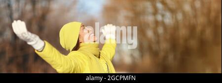 Inverno felice Asiatico ragazza rilassante godendo freddo tempo indossando caldi accessori sciarpa, cappello, guanti sorridenti con banner panorama a braccia aperte. Escursione in Foto Stock