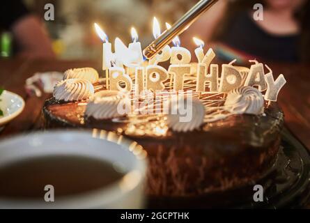 Torta con l'iscrizione buon compleanno con candele brucianti. Foto Stock