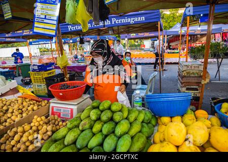 Commercianti di verdure in un mercato fresco a Putrajaya, vicino alla capitale Kuala Lumpur. Donna islamica con hijab vende verdure. A causa di Covid-19 indossa f Foto Stock
