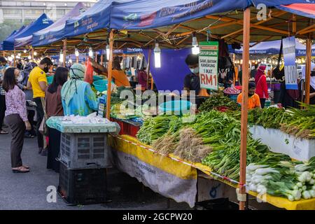 Commercianti di verdure in un mercato fresco a Putrajaya, vicino alla capitale Kuala Lumpur. Donna islamica con hijab vende verdure. A causa di Covid-19 indossa f Foto Stock