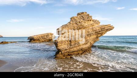 Rocce in acqua, onde che si infrangono contro le rocce, spiaggia sabbiosa con scogliere rocciose, Paralia Paradisos, Kos, Dodecanese, Grecia Foto Stock