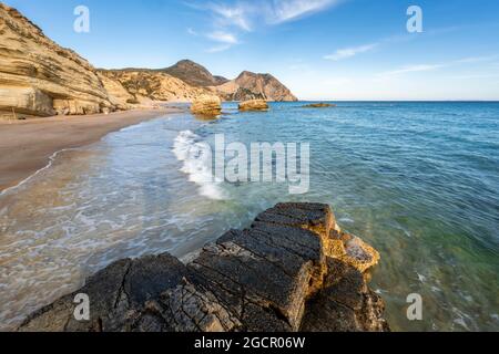 Onde che si infrangono contro rocce, spiaggia sabbiosa con scogliere rocciose, Paralia Paradisos, Kos, Dodecanese, Grecia Foto Stock