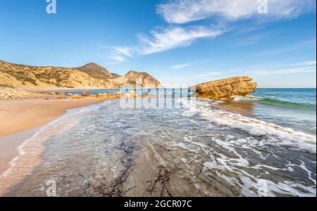 Rocce in acqua, onde che si infrangono contro le rocce, spiaggia sabbiosa con scogliere rocciose, Paralia Paradisos, Kos, Dodecanese, Grecia Foto Stock
