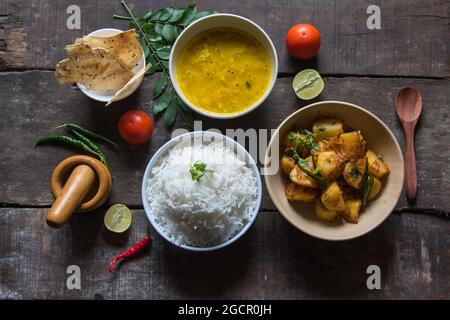 Vista dalla cima del semplice cibo indiano o pasto con patate fritte, riso, lenticchie, papad e condimenti. Piatto vegetariano. Foto Stock