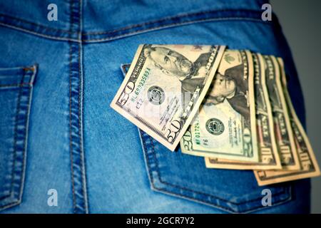 Una collezione di dollari USA in una tasca di jeans femmina, un po 'di soldi tascabili, vicino a 50 dollari. Dollari americani bloccati nella tasca della donna. Il dollaro t Foto Stock