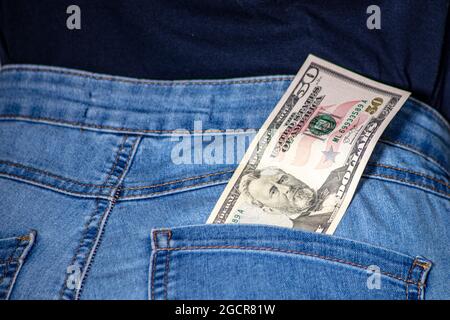 50 dollari in una tasca di jeans femminile. Banconote americane da cinquanta dollari attaccate in una tasca di jeans donna. Cinquanta dollari americani appesi in jeans donna. Denim e mone Foto Stock