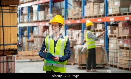 Addetto al magazzino che controlla le confezioni su scaffale in un grande negozio Foto Stock