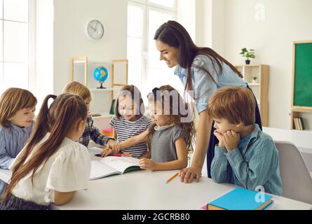 Gruppo di bambini felici della scuola e loro insegnante che hanno una classe in classe Foto Stock