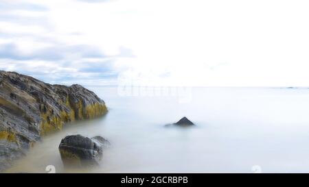 La lunga esposizione crea un effetto d'acqua setosa sulle onde dell'Oceano Atlantico, rompendo le rocce sulla costa del Maine Foto Stock